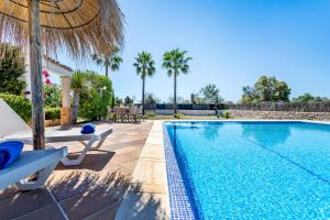 a swimming pool with two chairs and an umbrella at Chalet Irene by dracmallorca in Santanyi