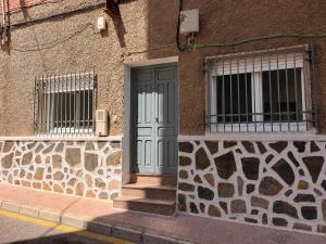 a building with a blue door and two windows at Cala de Los Lobos in Puerto de Mazarrón