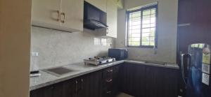 a kitchen with wooden cabinets and a stove top oven at Villa Riviera in Covelong