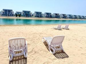 three beach chairs sitting on the sand on the beach at Luxury Sea Living in Sharjah