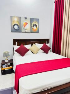 a bedroom with a large bed with red curtains at MSGuest House in Jaffna