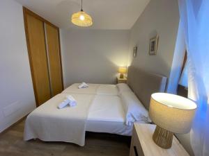 a small bedroom with a white bed and a lamp at R2R - Apartamentos Prellezo - C20C03 in Prellezo +31 photos