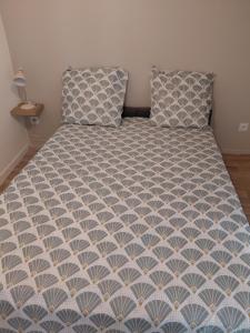 a bed with a blue and white comforter and two pillows at Studio le 174 in Mazan