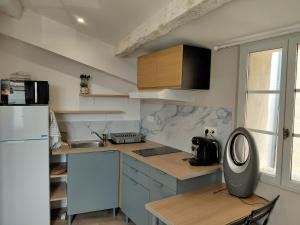 a kitchen with a refrigerator and a table with a fan at Studio le 174 in Mazan