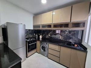 a kitchen with a stainless steel refrigerator and a dishwasher at Super Appartement Sidi Rhal in Dar Hamida