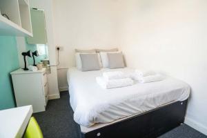 a bedroom with a bed with white sheets and pillows at Budget En-suite Room in Coventry City Centre in Coventry +37 photos