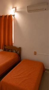 two orange beds in a room with a window at Casa Solymar completa 3 dormitorios 5 camas Hasta 6 personas RESERVAS SOLO CON SEÑA in Ciudad de la Costa