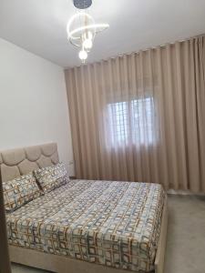 a bedroom with a bed and a window with curtains at Super Appartement Sidi Rhal in Dar Hamida