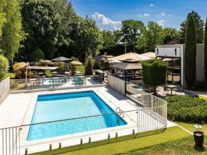 a swimming pool in a yard with tables and chairs at Novotel Marne La Vallée Collégien in Collégien