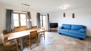 a living room with a blue couch and a table at Kramerhof - Ferienwohnung Zugspitze in Aufhofen