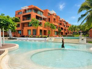 a woman standing in a swimming pool in front of a building at Las Tortugas beach front condo in Khao Tao