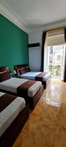 a room with three beds and a green wall at Kmt Hostel in Cairo
