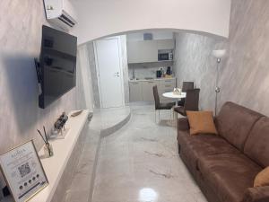 a living room with a brown couch and a kitchen at Romantic Suite Genova in Genoa