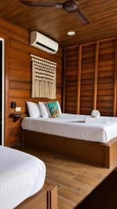 a bedroom with two beds in a room with wooden walls at Hotelito Villas Holbox - Self Check In in Holbox Island