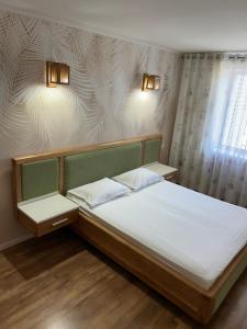 a bedroom with a bed with white sheets and a window at Простора та стильна 2 кімнатна в центрі Черкас на бульварі Шевченко з панорамним видом та СмартТВ! Дві окремі охайні спальні з кондиціонерами,поруч парковка з охороною in Cherkasy