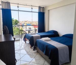 a hotel room with two beds and a balcony at Regency Plaza Hotel in Pisco