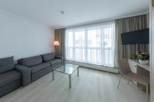 a living room with a couch and a tv at Michels Strandhotel Germania in Norderney