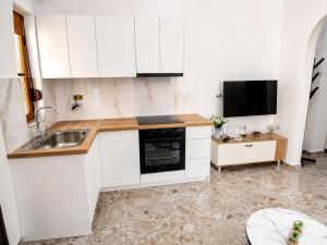 a kitchen with white cabinets and a sink and a tv at GUGA Host House in Sarandë