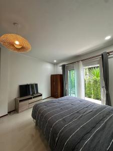 a bedroom with a bed and a television and a window at Golden Moon Resort in Ban Madua Wan