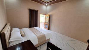 a bedroom with a large bed and a window at Homestay Sadikin Scar Reef Beach Jelenga in Maluk
