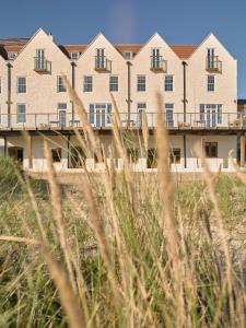a building on the beach with grass in the foreground at Braye Beach Hotel, Alderney in Alderney