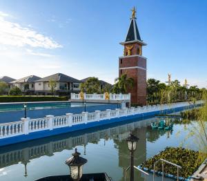 a building with a clock tower next to a body of water at Holi PTY Hotel in Ban Huai Yai