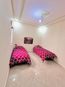 two beds in a room with red pillows at Mhamid 4 in Marrakesh