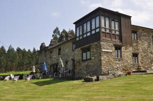 a large stone house with a black roof at O Plantio in O Porto de Espasante
