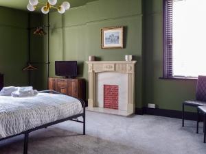 a bedroom with a fireplace and a bed and a tv at Cheshire Yeoman - Station Hotel in Hooton Station