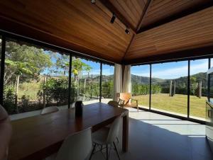 a dining room with a table and chairs and large windows at Nosso Loft Sebollas - 4C in Paraíba do Sul