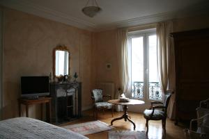 een slaapkamer met een bed en een televisie en een tafel bij Chambres d'hôtes Le Clos d'Hauteville in Le Mans