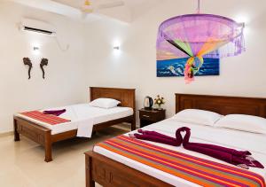 a bedroom with two beds and a painting on the wall at Ravan Safari Rest Inn in Udawalawe +87 photos
