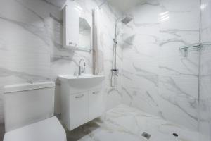 a white bathroom with a sink and a shower at Къща за гости Вихрен-Сандански in Sandanski +37 photos