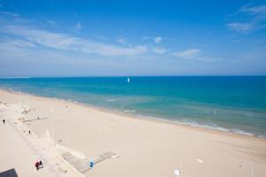 a sandy beach with a boat in the ocean at Apartamentos Guillem in Playa de Miramar