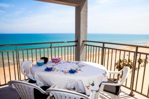 a table on a balcony with a view of the beach at Apartamentos Guillem in Playa de Miramar