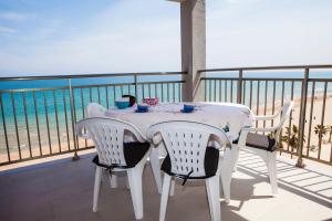 a white table and chairs on a balcony with the beach at Apartamentos Guillem in Playa de Miramar