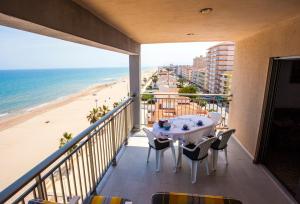 a balcony with a table and chairs and the beach at Apartamentos Guillem in Playa de Miramar