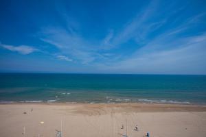 a beach with people standing on the sand and the ocean at Apartamentos Guillem in Playa de Miramar