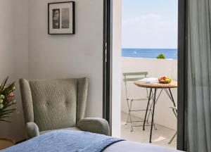 a bedroom with a chair and a table with a view of the ocean at Les Hautes Mers - Fontenille Collection in L'Ile d'Yeu