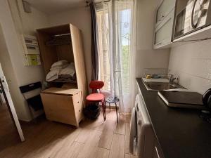 a small kitchen with a sink and a counter with a chair at Duplex moderne & calme à Malakoff in Malakoff