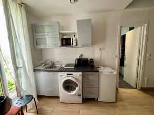 a kitchen with a washing machine and a microwave at Duplex moderne & calme à Malakoff in Malakoff +8 photos
