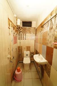a small bathroom with a toilet and a sink at Udhaya Lodge in Rāmeswaram