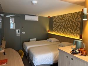 a hotel room with two beds and a desk with a desk at Green Hôtels Poitiers in Poitiers