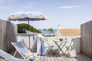a patio with a table and chairs and an umbrella at Les Hautes Mers - Fontenille Collection in L'Ile d'Yeu