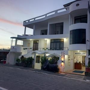 a large white building with an umbrella on a street at Hostal Cerro Azul in Puerto Villamil
