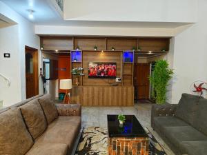 a living room with a couch and a tv at Majestic Villa, 5 Bedroom AC in Mysore in Mysore