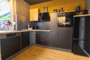 a kitchen with stainless steel appliances and black cabinets at Kleine Austernperle in Dornumersiel +8 photos