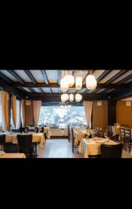 a restaurant with tables and chairs and a large window at Hôtel La Redoute in Les Rousses