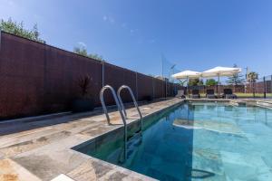 a swimming pool with two metal railings in front of a wall at Villa Thiago in Cádiz