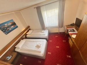 a small hotel room with two beds and a desk at Hotel Kaiserquelle in Salzgitter